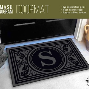 May include: A black doormat with a gray damask pattern and the letter "S" in a circle. The doormat has black finished edges and a Durgan rubber bottom. The text "DAMASK MONOGRAM DOORMAT" is at the top of the image.