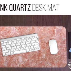 May include: Pink quartz desk mat with a white keyboard and a white computer mouse. The mat has a pink and white marbled pattern.