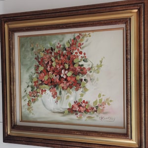 May include: A framed painting of a bouquet of red flowers in a white vase. The flowers are painted in a realistic style and the background is a soft green. The painting is signed "D.Courtney" in the bottom right corner.