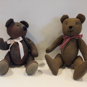 May include: Two brown teddy bears with different colored ribbon accents. One bear has a white ribbon and the other has a red and white striped ribbon.