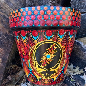 May include: A terracotta flower pot painted with a colorful mandala design featuring a black and yellow Grateful Dead Steal Your Face logo in the center.