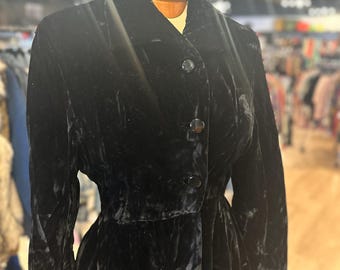 May include: A black velvet coat with a button closure and a fitted waist. The coat has a long sleeve and a classic collar.