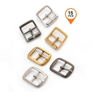 Puede incluir: Un surtido de hebillas metálicas para cinturón en varios acabados, incluyendo plata, oro y metal de cañón. Las hebillas son cuadradas con una sola espiga y se muestran sobre un fondo blanco. Un gráfico indica que hay 15 piezas.