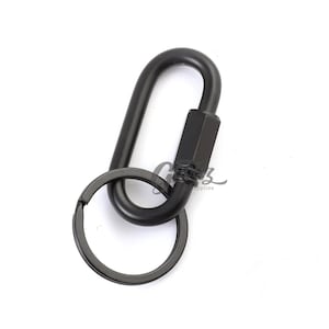 May include: Black metal carabiner with a key ring attached. The carabiner has a spring-loaded gate and a swiveling top.