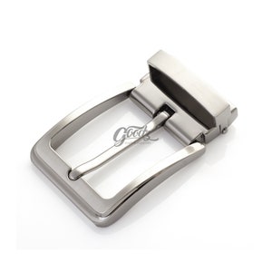 May include: A silver metal belt buckle with a rectangular shape and a smooth, brushed finish.