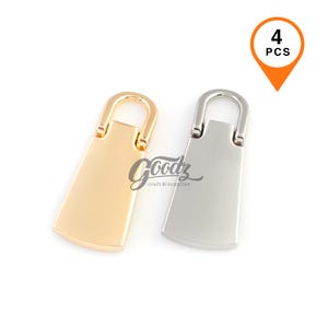 Puede incluir: Dos tiradores de cremallera metálicos, uno dorado y otro plateado, con forma rectangular y parte superior curvada. Los tiradores son para proyectos de artesanía y suministros. La imagen incluye un gráfico que dice "4 PCS".