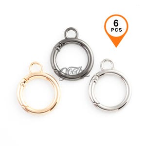 May include: Three round metal clasp rings in gold, gunmetal, and silver. Each ring has a spring-loaded clasp and a small loop at the top. A tag indicates there are 6 pieces.