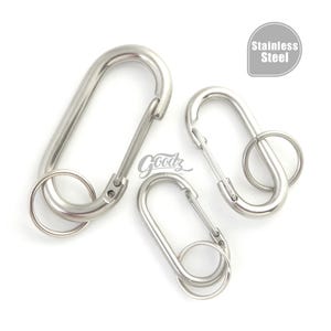 Pode incluir: Três mosquetões de aço inoxidável de tamanhos variados, cada um com um porta-chaves. Os clipes são prateados e têm um acabamento liso e brilhante. O texto "Stainless Steel" está num círculo cinzento.