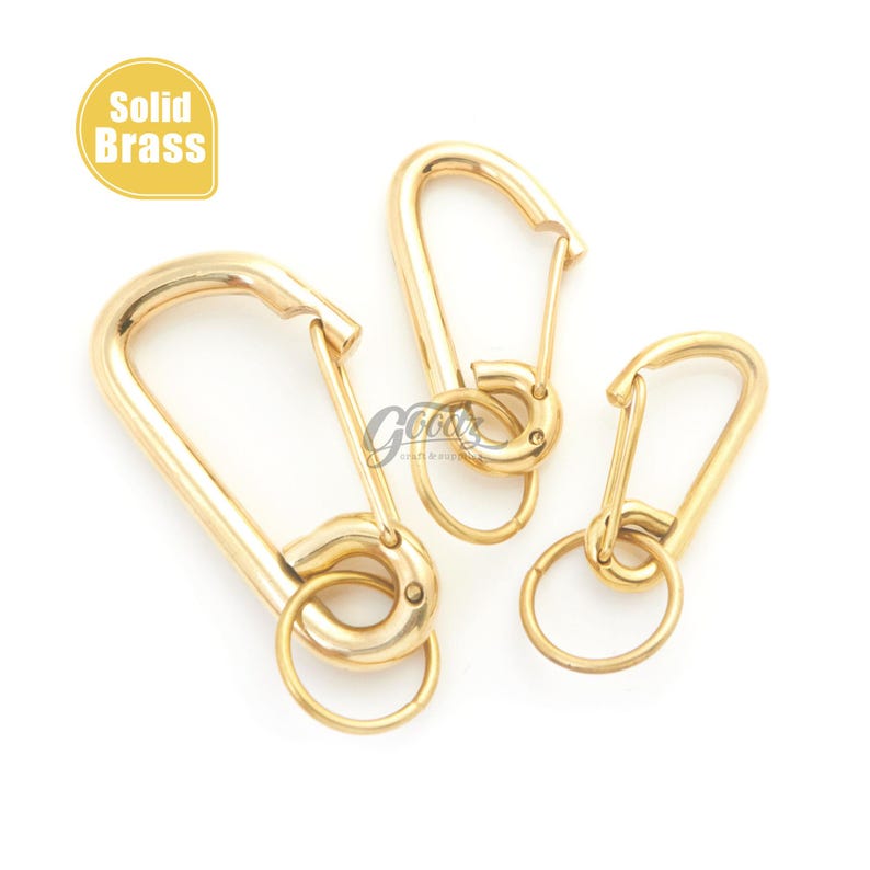 Puede incluir: Tres mosquetones de lat&oacute;n macizo dorados de diferentes tama&ntilde;os, con anillas para llaves. Los mosquetones tienen un acabado liso y pulido. En la esquina superior izquierda hay un &oacute;valo amarillo con la inscripci&oacute;n "Solid Brass".