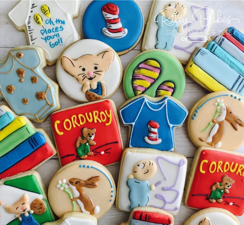 May include: A collection of decorated sugar cookies featuring characters and book covers from popular children's books, including "Corduroy", "Where the Wild Things Are", "The Cat in the Hat", and "Guess How Much I Love You".