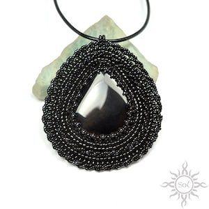 May include: Black beaded necklace with a teardrop-shaped black gemstone pendant.