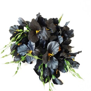 May include: A bouquet of black silk flowers with yellow centers and green stems.