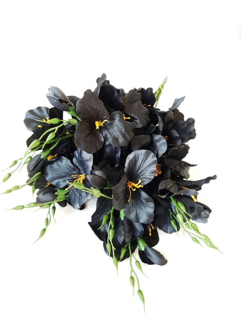 May include: A bouquet of black silk flowers with yellow centers and green stems.