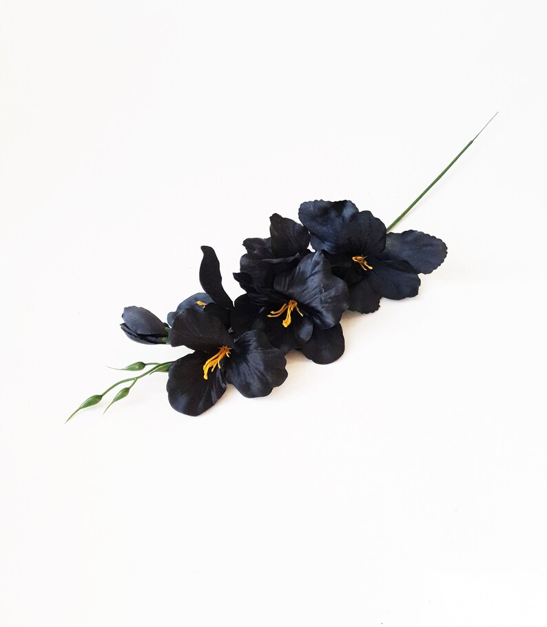 May include: A bunch of black silk gladiolus flowers with yellow centers. The flowers are arranged in a line and have a green stem.