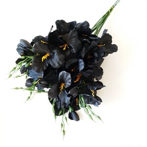 May include: A bouquet of black silk flowers with yellow centers and green stems.