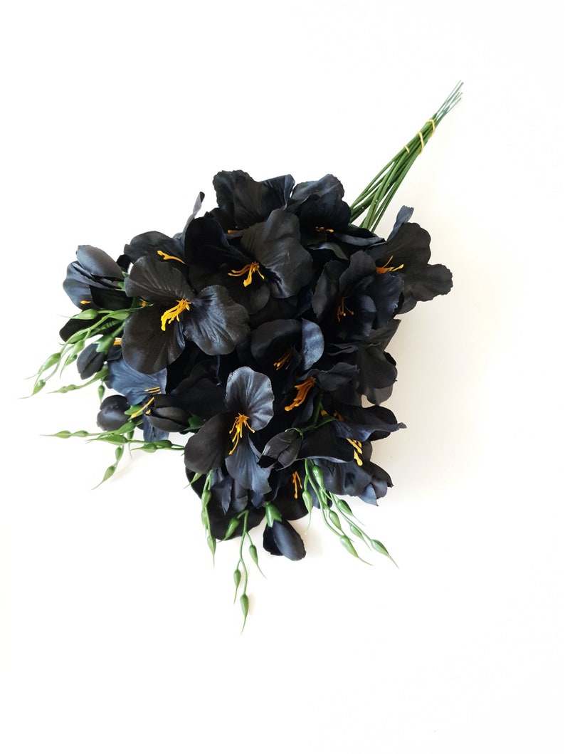 May include: A bouquet of black silk flowers with yellow centers and green stems.