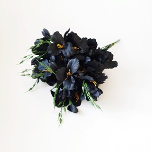May include: A bouquet of black silk flowers with yellow centers and green stems.