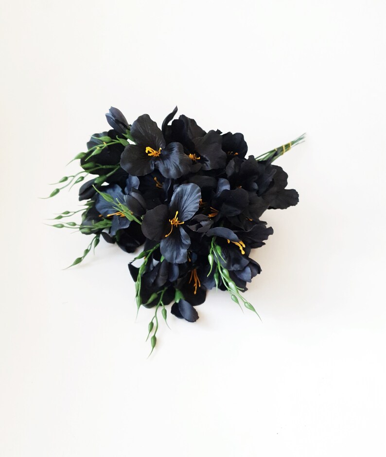 May include: A bouquet of black silk flowers with yellow centers and green stems.