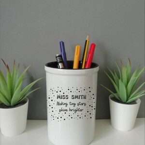 May include: White ceramic pencil holder with black stars and the text "Miss Smith Making tiny stars shine brighter".
