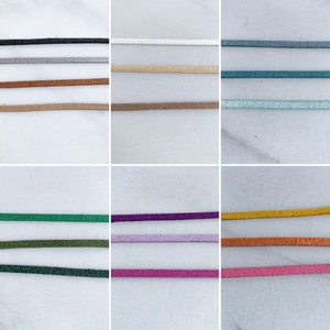 K&ouml;nnte beinhalten: Eine Sammlung d&uuml;nner, glitzernder Kordeln in verschiedenen Farben, darunter Schwarz, Silber, Bronze, Beige, Braun, Wei&szlig;, T&uuml;rkis, Hellblau, Gr&uuml;n, Olive, Dunkelgr&uuml;n, Lila, Lavendel, Rosa, Gold, Orange und Pink. Die Kordeln sind vor wei&szlig;em Hintergrund dargestellt.