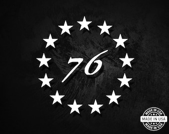 May include: A black and white graphic design featuring a circle of stars surrounding the number "76". The text "MADE IN USA" is printed in a circle with stars around the text.
