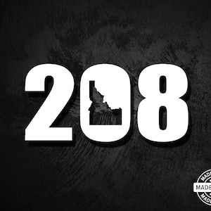 May include: White numbers 208 with an outline of the state of Idaho in the middle. The background is black with a distressed texture. The text "MADE IN USA" is in a circle with stars around it.
