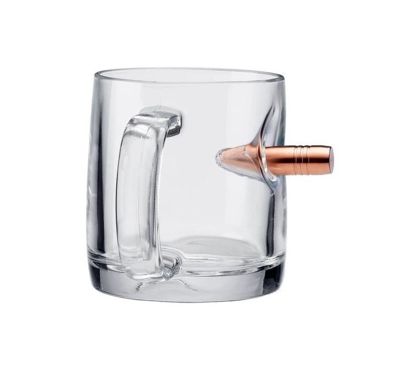 May include: A clear glass mug with a copper-coloured bullet embedded in the side, serving as the handle.