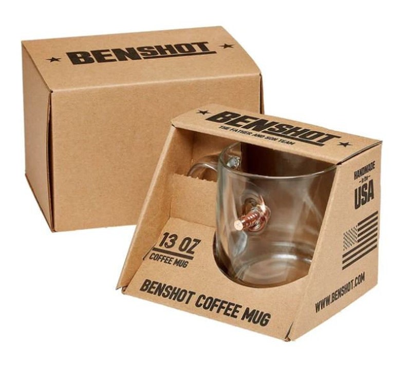 May include: A brown cardboard box with the text "BENSHOT" printed on the top. The box contains a clear glass coffee mug with a bullet-shaped handle. The mug is labelled "13 oz Coffee Mug" and "BENSHOT COFFEE MUG". The box also has the text "Handmade in the USA" and "www.benshot.com" printed on it.
