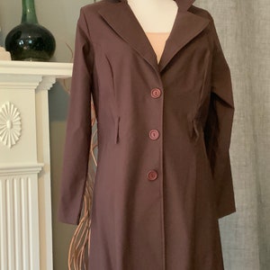 May include: A long brown coat with a collar and five buttons down the front.
