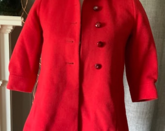 May include: A red wool coat with a collar and four red buttons. The coat has a slightly flared hem and three-quarter sleeves.