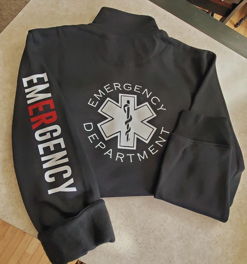 May include: Black zippered jacket with white text on the sleeves that reads "EMERGENCY" and a white star of life logo on the back with the text "EMERGENCY DEPARTMENT".