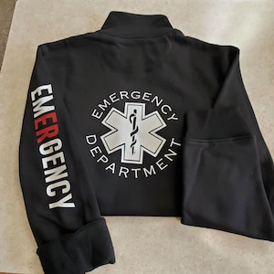 May include: Black zippered jacket with the words "EMERGENCY DEPARTMENT" in white lettering and a white star of life symbol on the back. The words "EMERGENCY" are printed in red on the left sleeve.