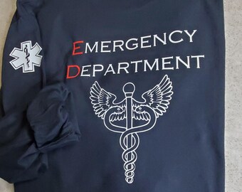 May include: A dark blue long-sleeved shirt with the words "EMERGENCY DEPARTMENT" in white lettering and a red "E" and "D". A white medical symbol with a snake and wings is below the text.