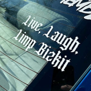 May include: A blue car window with a white sticker that says "Live, Laugh, Lip Bizkit" in a gothic font.