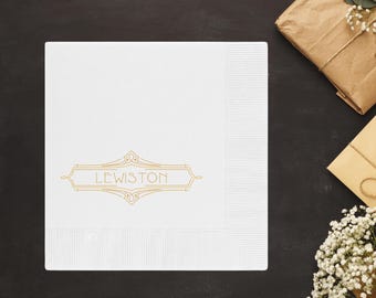 Pode incluir: Guardanapo de papel branco com um design art déco dourado e o nome "LEWISTON" impresso em dourado.