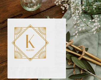 Pode incluir: Guardanapo de papel branco com um design geométrico dourado que apresenta a letra K e a data 05.20.2025.