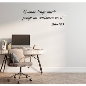 May include: A white wall with a black cursive quote in Spanish that reads "Cuando tengo miedo, pongo mi confianza en ti."  The quote is attributed to Salmo 56:3.  A desk with a computer monitor, a chair, and office supplies is in the foreground.