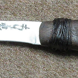 May include: A brown wooden handled knife with a silver blade. The blade has the text "URBAIN" etched into it. The handle has four brass rivets.