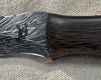 May include: A black and silver knife with a wooden handle. The blade has a wavy pattern and the handle is made of dark wood.