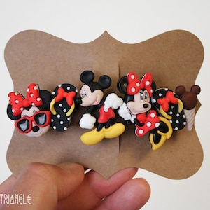 May include: Set of five colorful cartoon character hair clips featuring Mickey Mouse and Minnie Mouse. The clips are made of plastic and have a black and white polka dot pattern. The characters are wearing red and yellow clothing and accessories.