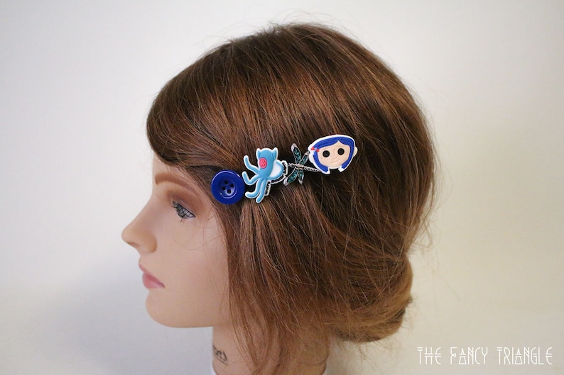 Puede incluir: Pinza para el pelo con un bot&oacute;n azul, un pulpo azul, una lib&eacute;lula y una ni&ntilde;a de dibujos animados. El accesorio para el cabello est&aacute; sujeto a cabello casta&ntilde;o. Un accesorio para el cabello &uacute;nico.