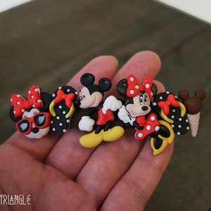 May include: A set of five colorful cartoon character charms featuring Mickey Mouse and Minnie Mouse. The charms are made of plastic and have a black, red, white, and yellow color scheme. The charms are perfect for adding a touch of Disney magic to any project.