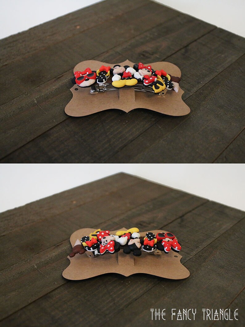 May include: A set of six colorful hair clips featuring Mickey Mouse and Minnie Mouse characters. The clips are made of plastic and have a variety of designs, including Mickey Mouse with sunglasses, Minnie Mouse with a bow, and a Mickey Mouse head. The clips are displayed on a brown card with the text "THE FANCY TRIANGLE".
