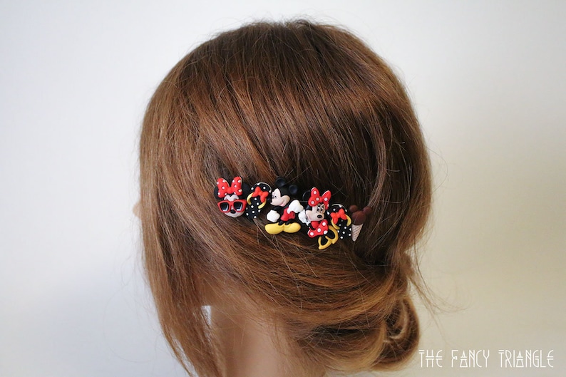 May include: A set of hair clips featuring various cartoon characters, including Mickey Mouse and Minnie Mouse. The clips are made of plastic and have a colorful design.