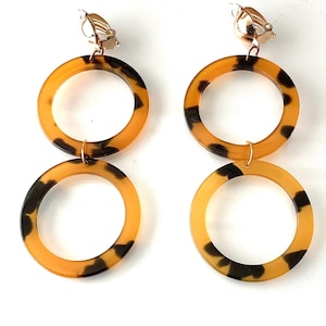 May include: A pair of clip-on earrings with a tortoiseshell pattern. The earrings are made of two overlapping circles.
