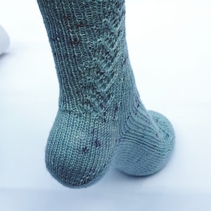 May include: A pair of blue knitted socks with a lacy pattern on the top of the foot.