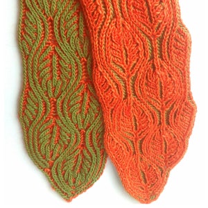 May include: Two knitted fabric swatches in a leafy pattern. One swatch is a deep green color and the other is a bright orange color.