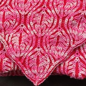 Op de afbeelding: Een roze en witte gehaakte babydeken met een bladmotief.