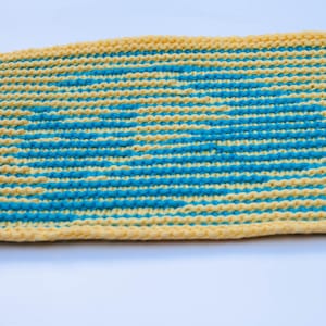 May include: A yellow and blue knitted dishcloth with a striped pattern. The dishcloth is made of cotton yarn and is perfect for cleaning dishes.