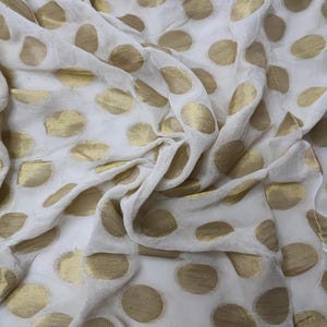 Peut inclure: Tissu blanc transparent à pois dorés. Le tissu est froissé et a une texture douce et fluide.